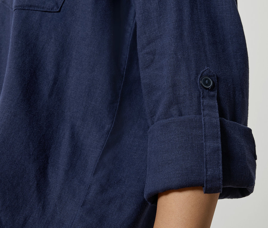 Nahaufnahme eines dunkelblauen Leinenhemdes mit hochgekrempelten Ärmeln und Knopfdetails.