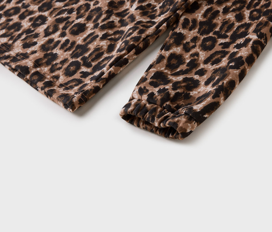 Nahaufnahme eines Ärmels mit Leopardenmuster und gerafftem Bündchen auf weißem Hintergrund.