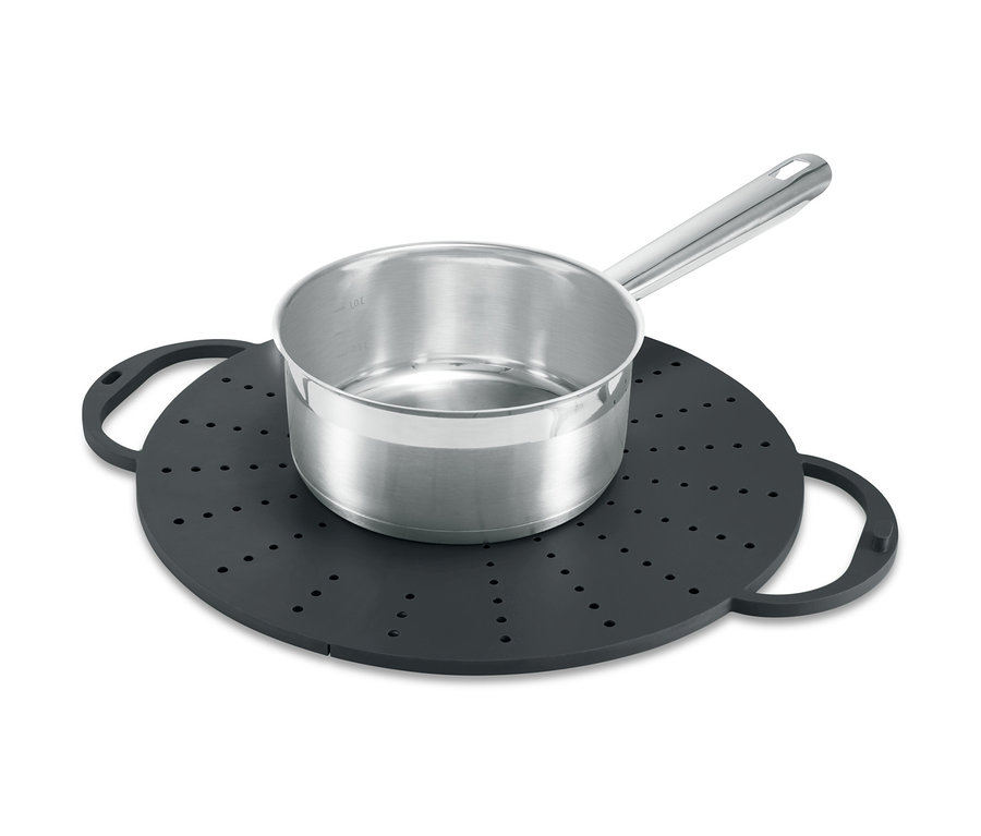 Ein Edelstahltopf steht auf einem schwarzen Küchen-Allrounder mit Löchern und Griffen.