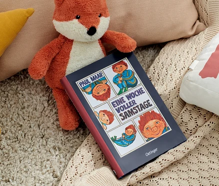 Ein Stofffuchs liegt neben dem Buch »Das Sams – eine Woche voller Samstage« und Kissen.