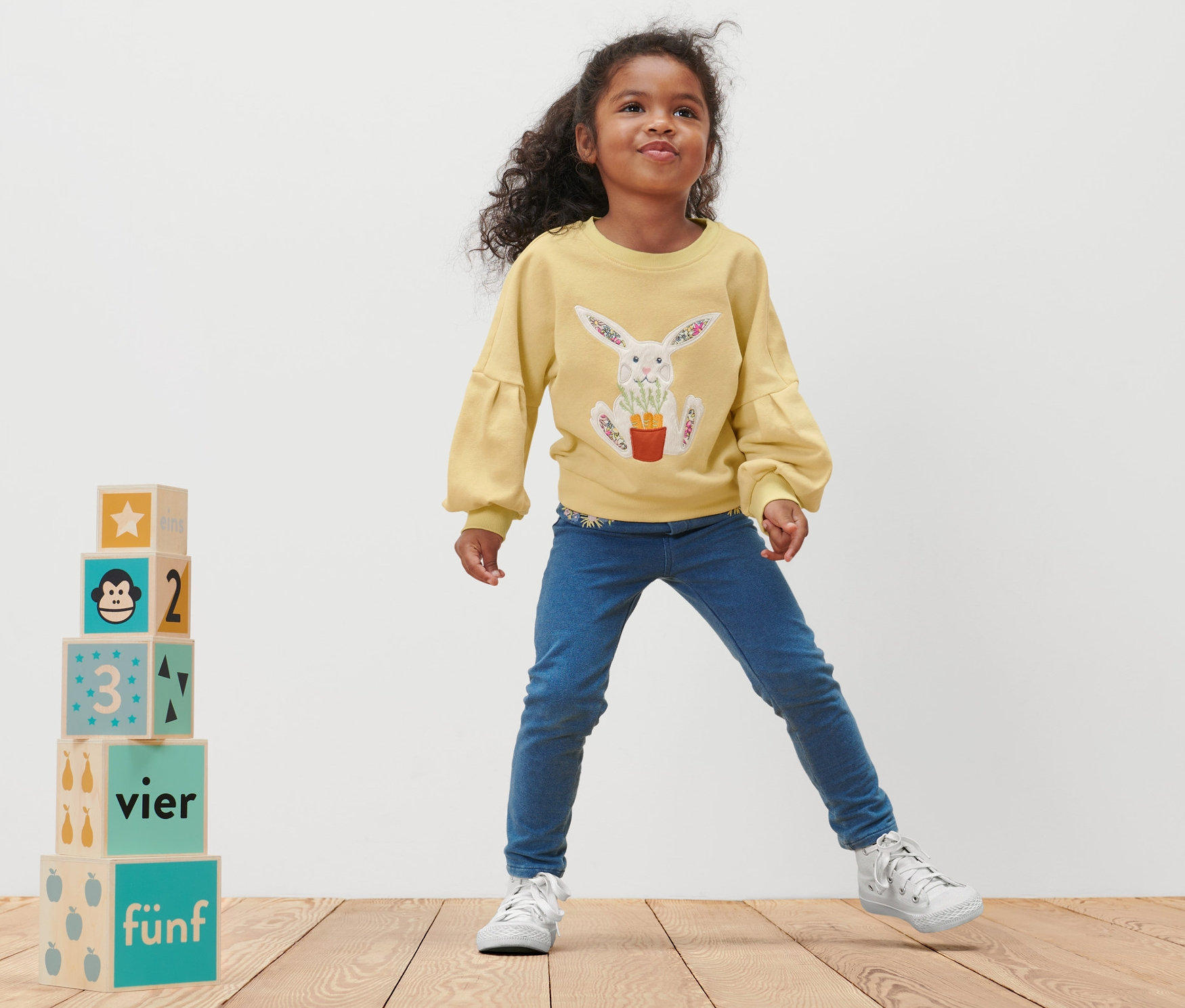 Mädchen posiert in einem Kleinkind-Sweatshirt mit Hasen-Aufdruck.