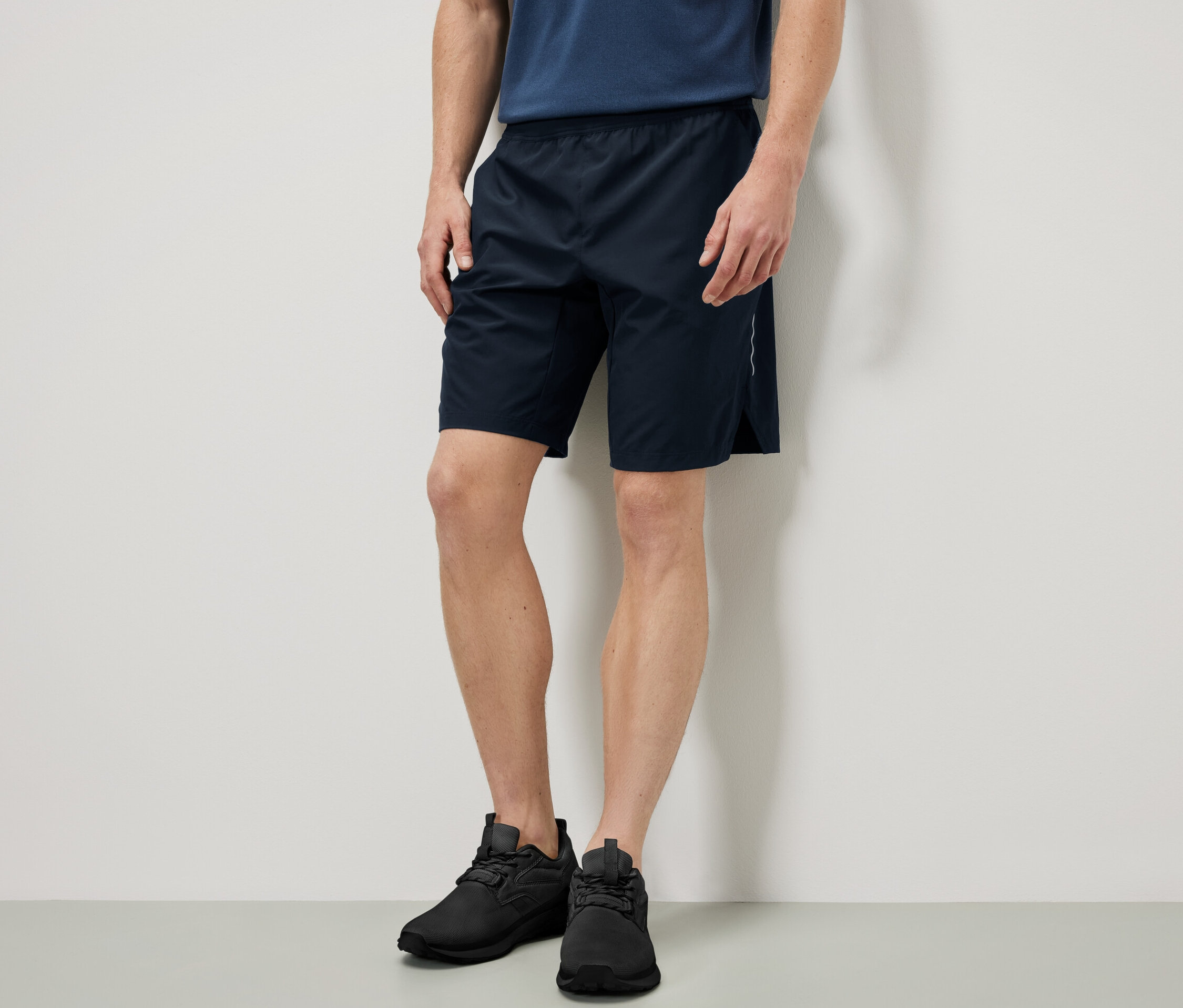 Mann steht und trägt Sportshorts.