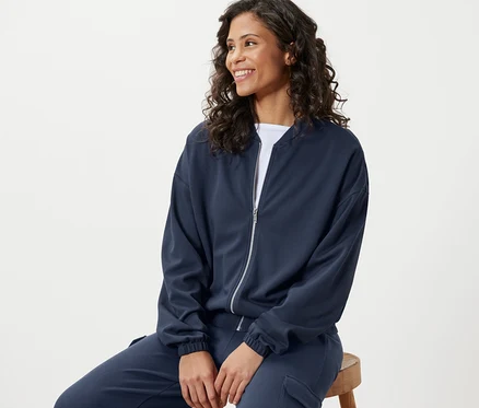 Frau sitzt und trägt eine blaue Sweatjacke.