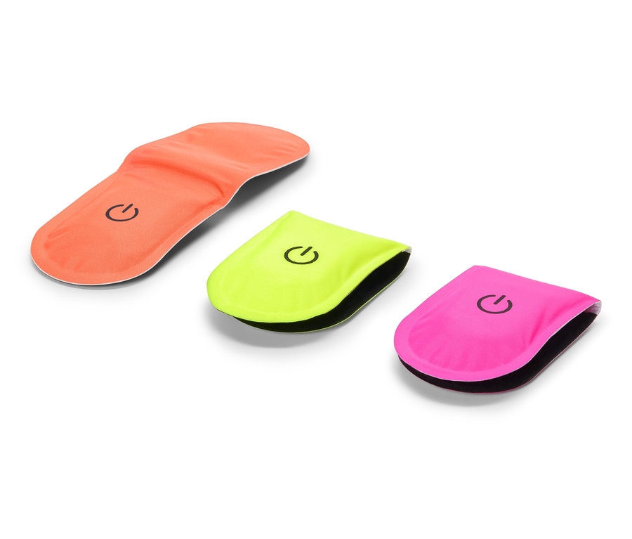 Orangefarbene Schuheinlage liegt neben gelbem und pinkem Blinklicht.