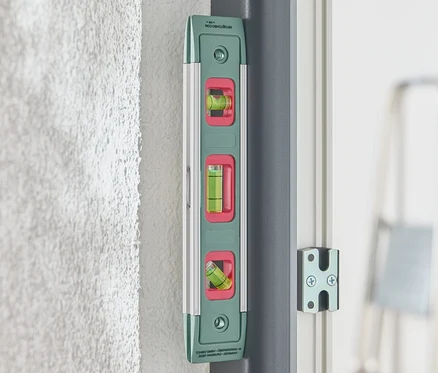 Eine grüne Magnet-Wasserwaage ist an einer Wand befestigt.