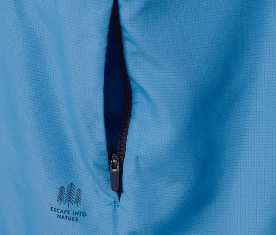 Detailansicht einer blauen Funktionsjacke, packable, mit Reißverschluss und dem Schriftzug Escape into nature.