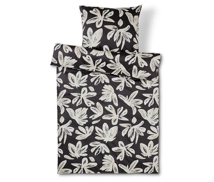 Schwarz-weisse Bettwäsche und Kissen mit Blumenmuster.
