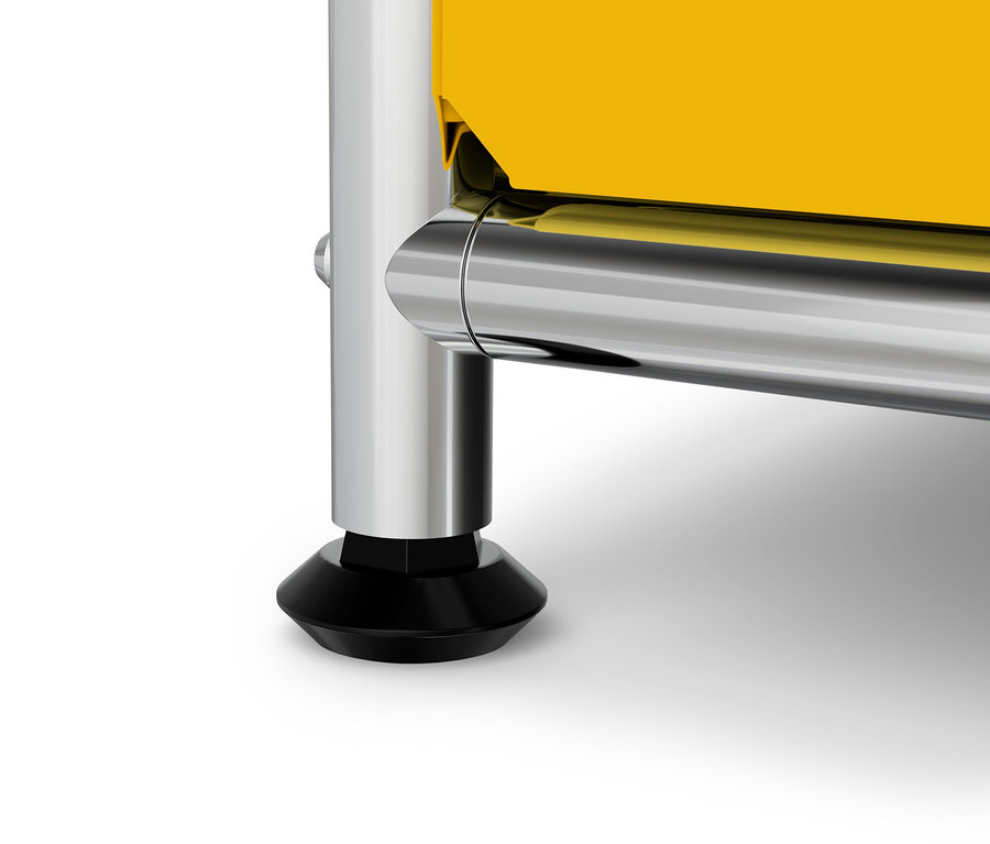 Detail eines gelben Möbels mit einem verchromten Bein und einem schwarzen Fuß.