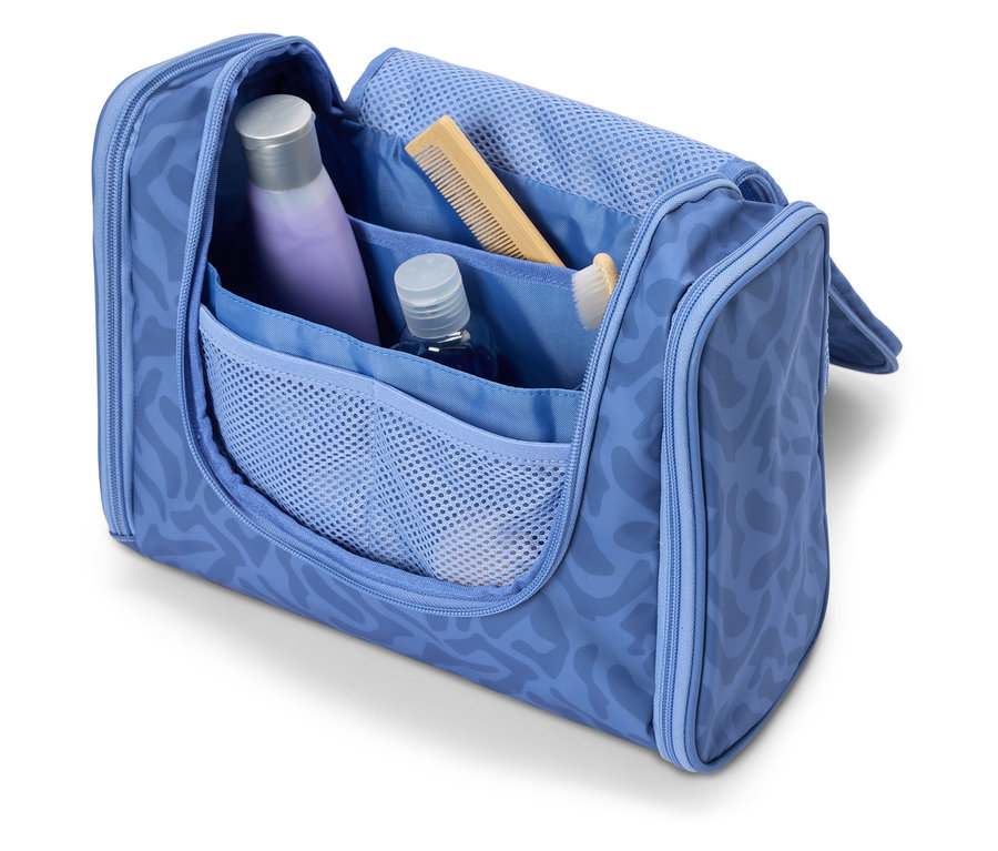 Offene, hellblaue Kosmetiktasche mit verschiedenen Reiseutensilien wie Shampoo, Kamm und Zahnbürste.