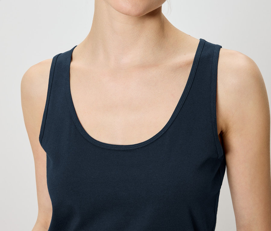 Nahaufnahme einer Frau, die ein ärmelloses, marineblaues Tanktop trägt.