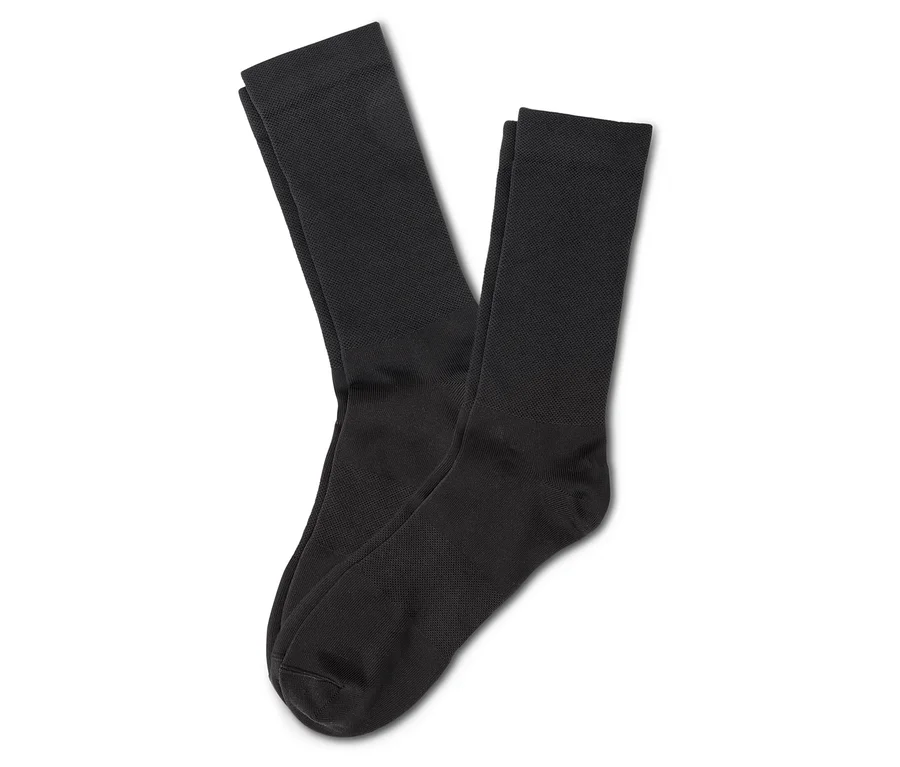 Zwei schwarze Socken liegen übereinander auf einem weißen Hintergrund.