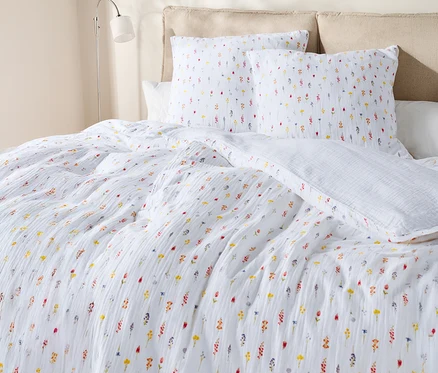 Nahaufnahme eines Bettes mit weißer Bettwäsche mit Blumenmuster und Kissen.
