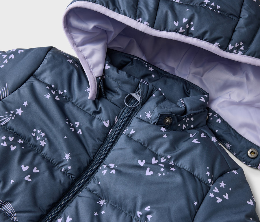 Nahaufnahme einer marineblauen, gesteppten Jacke mit Kapuze und Reißverschluss, verziert mit Herzen, Sternen und Kometen in Lila.