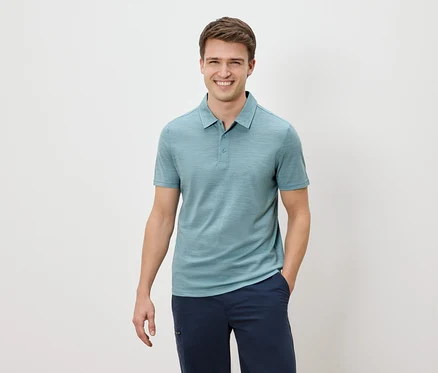 Mann lächelt und trägt ein blaues Polohemd und eine marineblaue Hose.