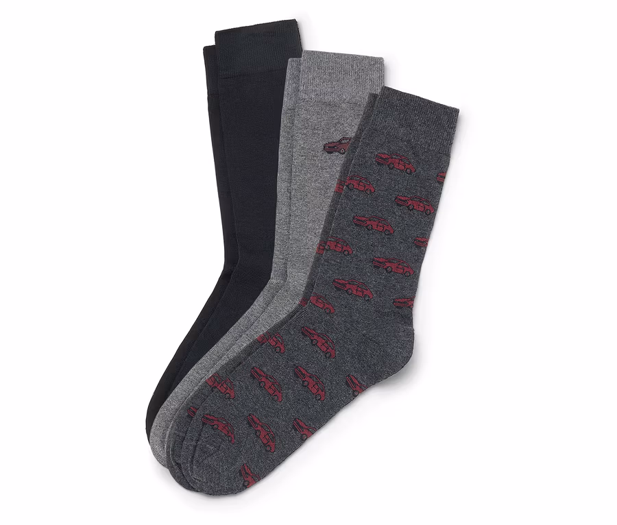 Drei Socken liegen übereinander: eine schwarze, eine graue und eine dunkelgraue mit roten Autos.
