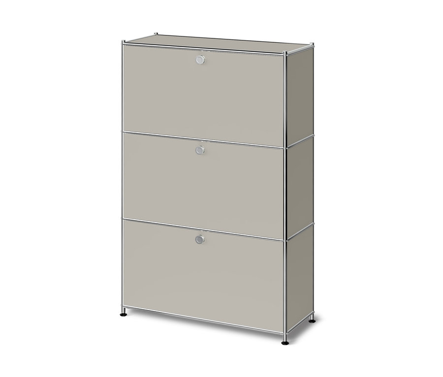 Helles beiges Modulschrank mit drei Klapptüren und einem Chromrahmen, auf kurzen schwarzen Füßen stehend.
