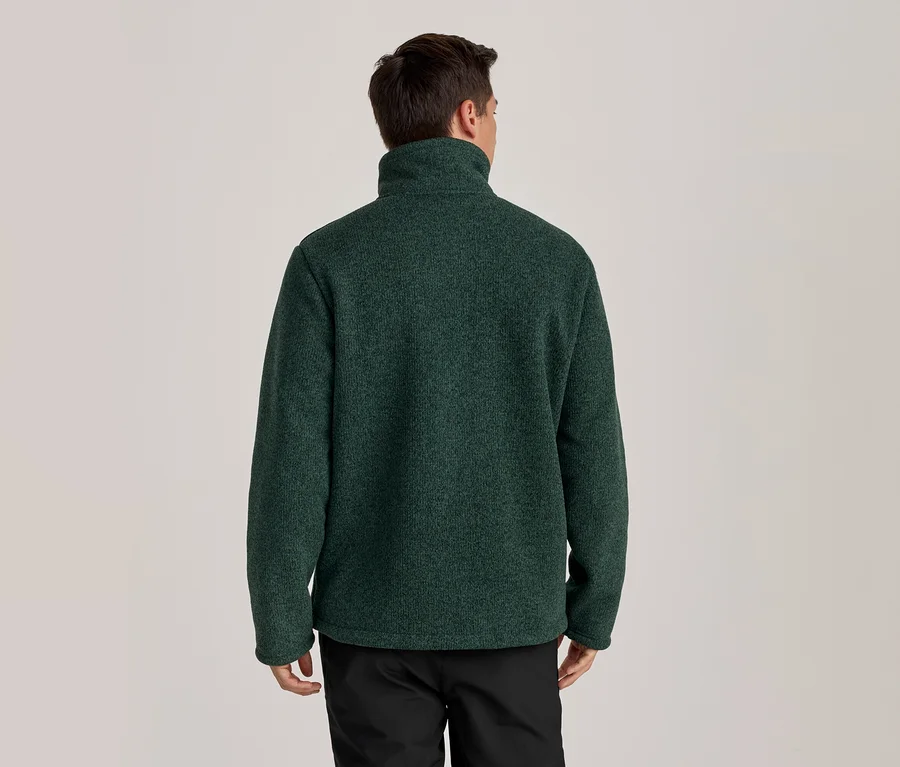 Mann von hinten in einer dunkelgrünen Fleecejacke mit Stehkragen und schwarzer Hose.