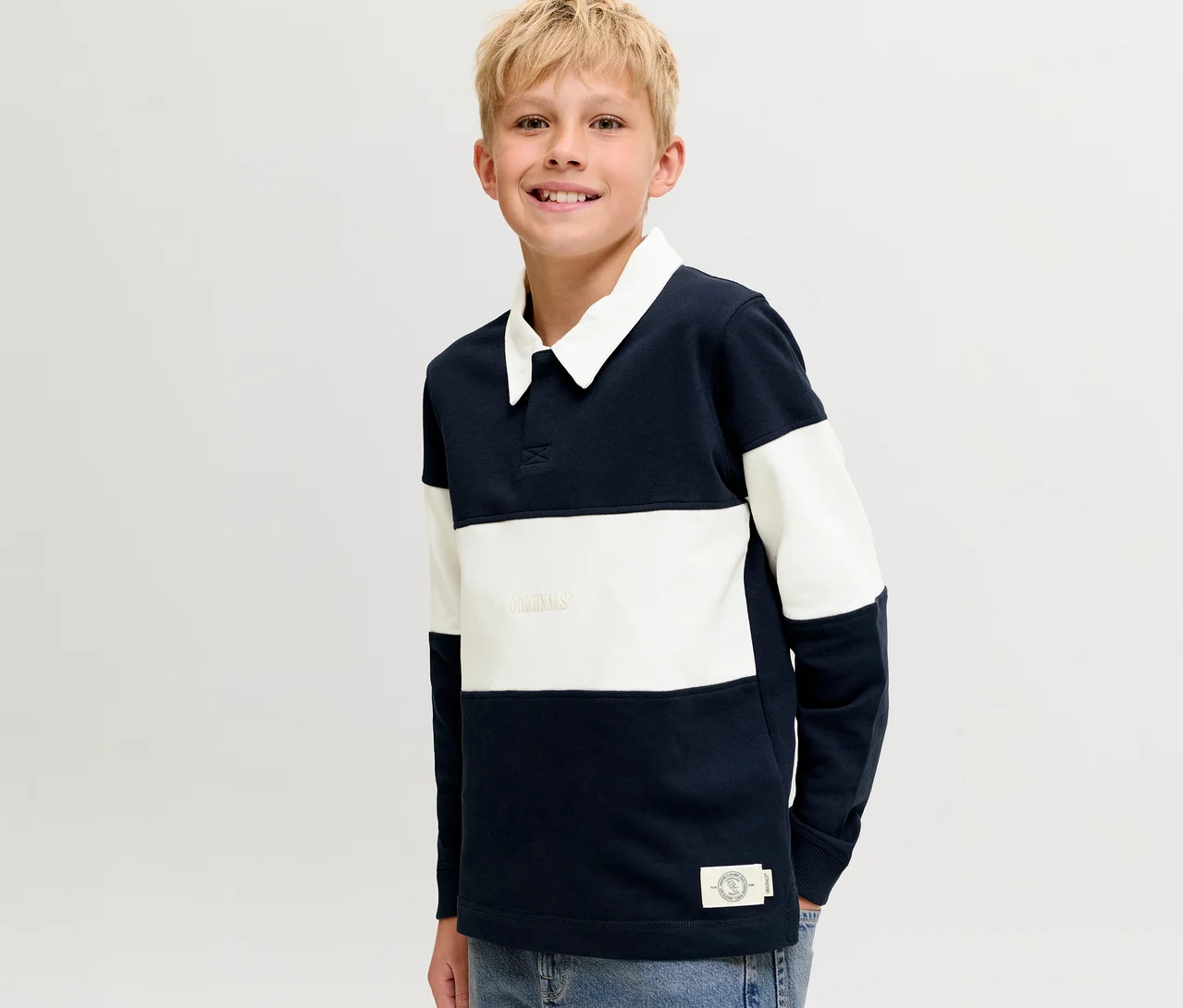 Lächelnder blonder Junge trägt einen blau-weiß gestreiften Jack&Jones Polo Sweater mit weißem Kragen.
