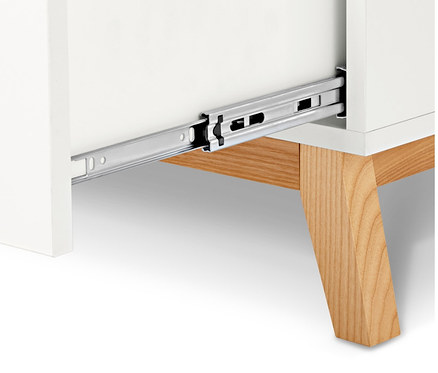 Detailansicht einer weißen Kommode mit offener Schublade und Holzfüßen.