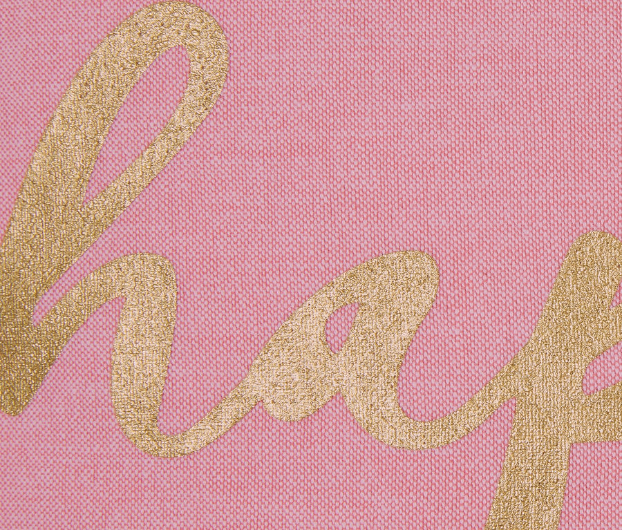 Nahaufnahme eines rosa Dekokissen-Bezugs mit goldenem Schriftzug.
