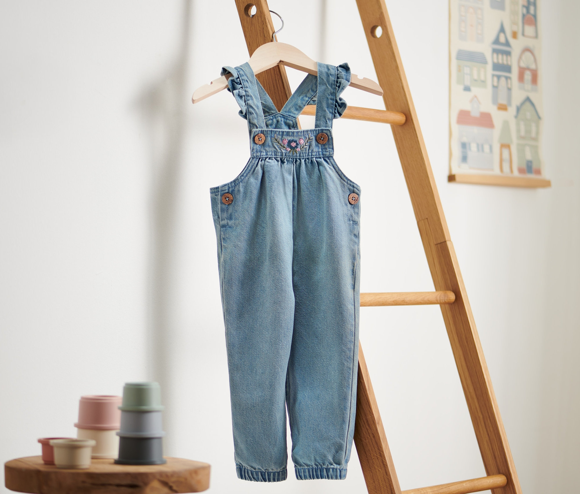 Eine Denim-Latzhose hängt an einer Holzleiter.