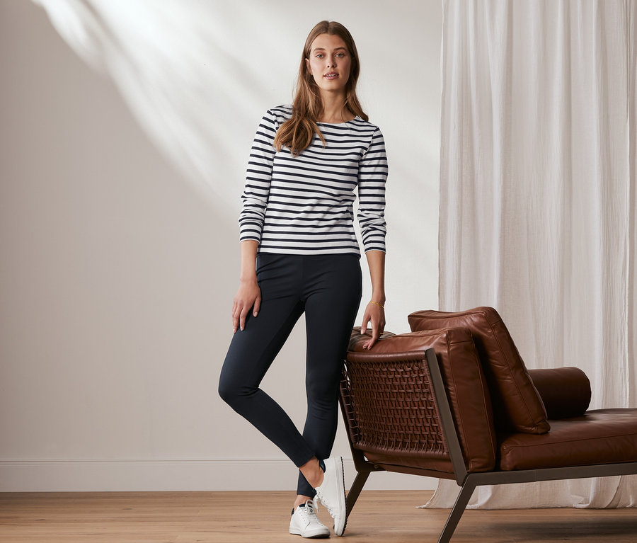 Eine Frau posiert an eine Ledercouch gelehnt und trägt eine Basic-Leggings aus Heavy-Jersey, dunkelblau.