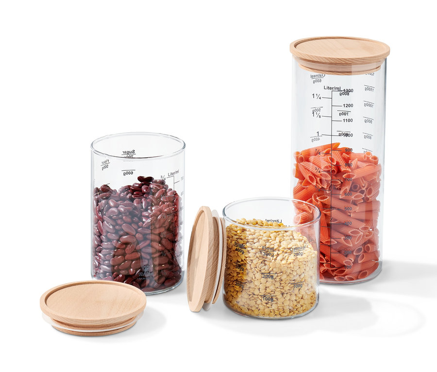 Drei Glas-Vorratsdosen-Sets mit Holzdeckeln, gefüllt mit roten Bohnen, Linsen und Teigwaren.