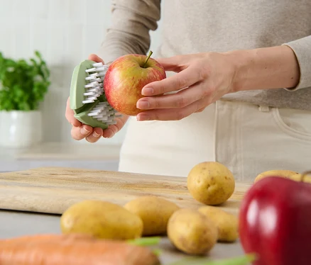 Frau putzt Apfel mit flexibler Gemüse-und-Obstbürste.