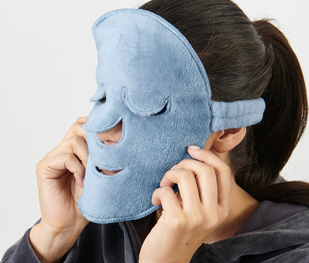 Frau setzt hellblaue 2 Gesichtsmasken auf ihr Gesicht.