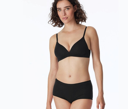 Frau trägt schwarze BH und 2 SCHIESSER Shorts mit Bio-Baumwolle, schwarz.