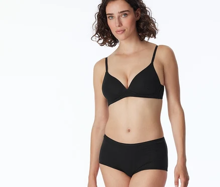 Frau trägt einen schwarzen BH und schwarze SCHIESSER Shorts.