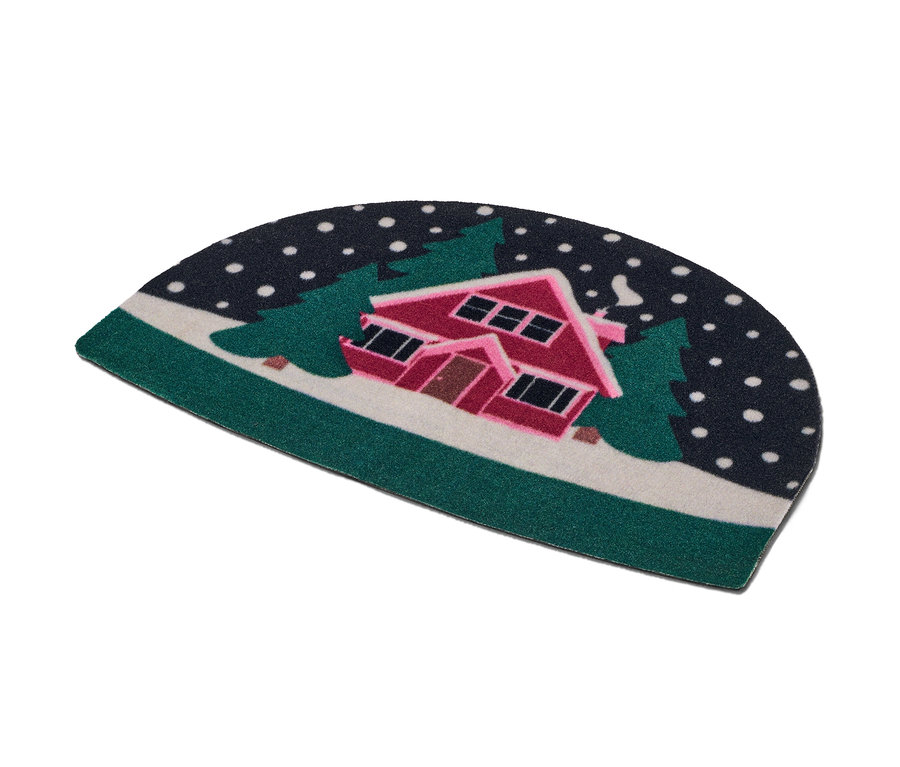 Fußmatte mit einem verschneiten Haus zwischen Bäumen.