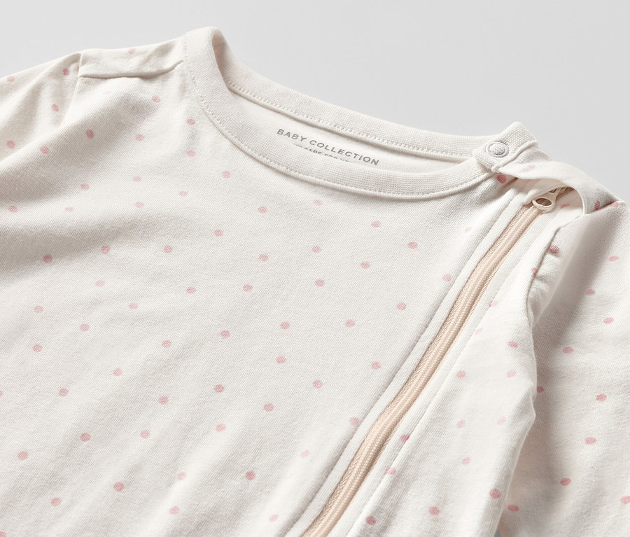 Detailansicht eines Baby-Schlafanzugs mit rosa Punkten und Reißverschluss. 3 Baby-Pyjamas, Prinzessin.