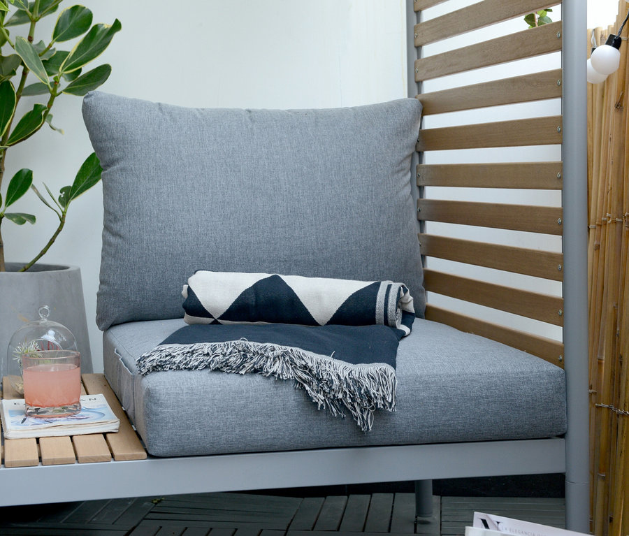 Graue ScanCom Outdoor-Lounge mit Fußhocker und einer zusammengerollten Decke.
