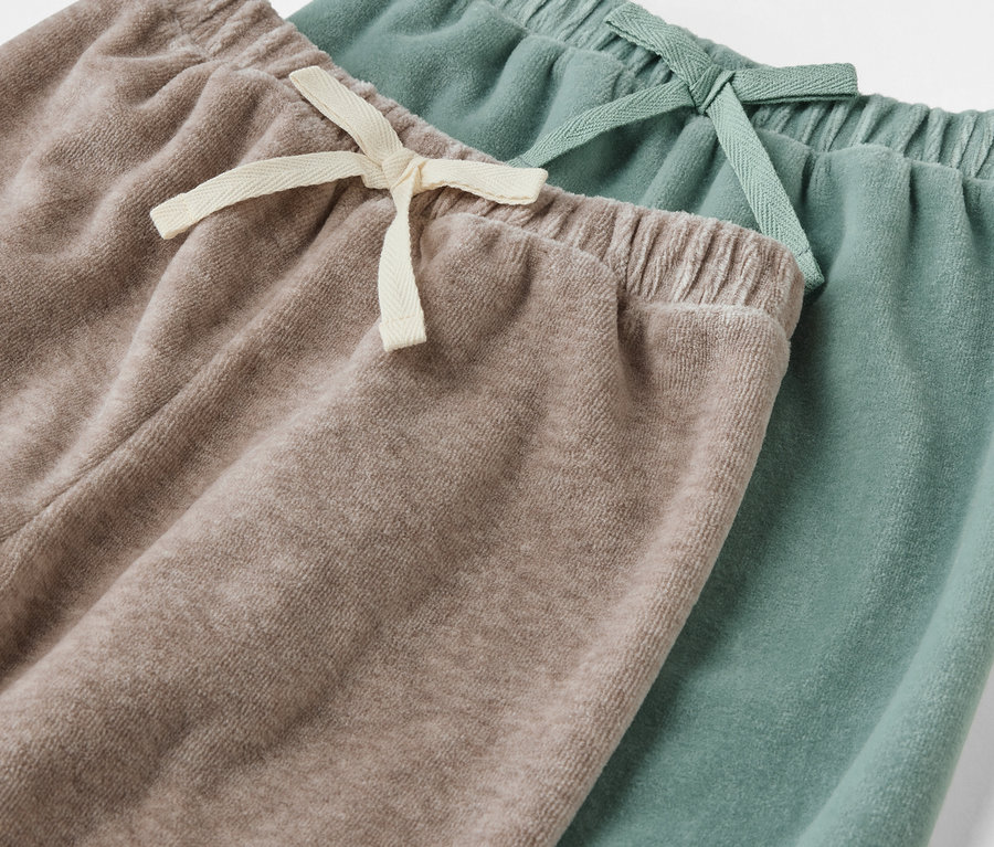 Detailansicht von zwei Paar Baby-Pull-on-Pants, eine beige, eine grün.