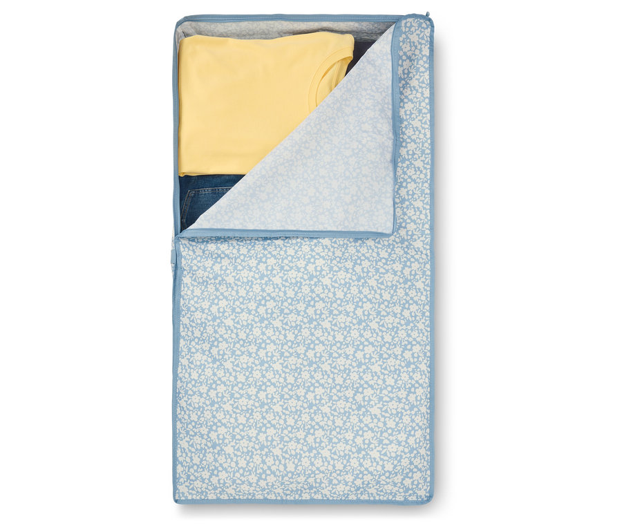 Geöffneter Kleidersack mit blauem Blumenmuster und gelbem T-Shirt und Jeans darin.