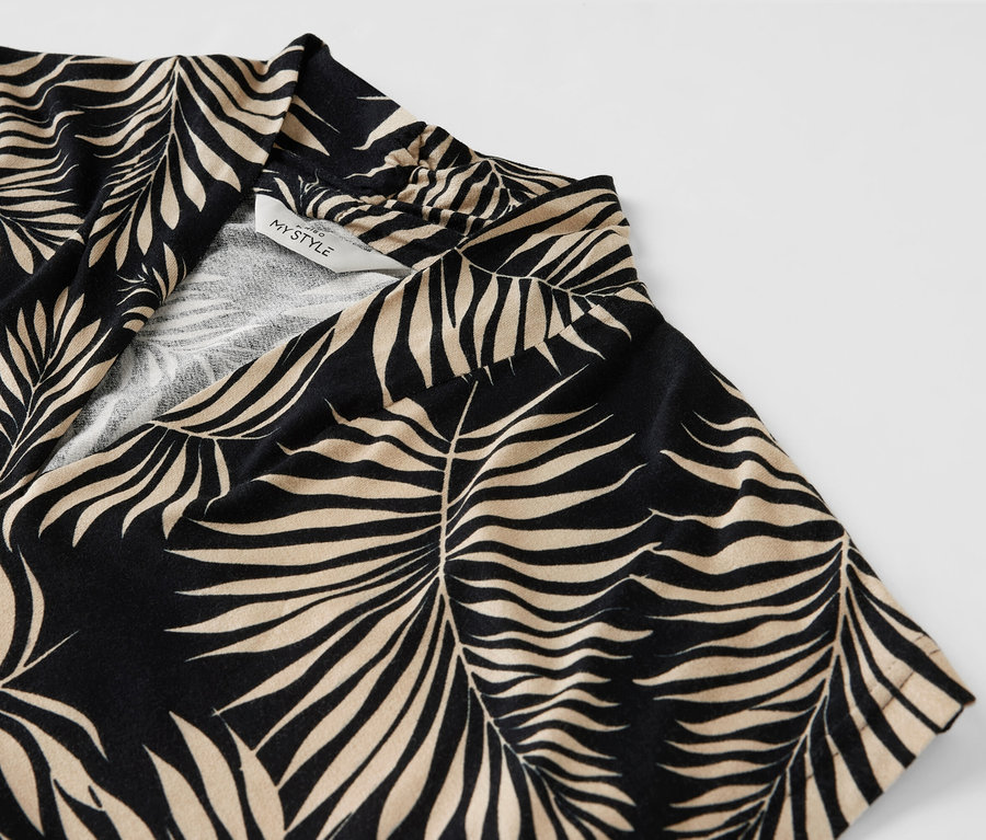 Detailansicht eines bedruckten Blusenshirts mit V-Ausschnitt und Blattmuster.