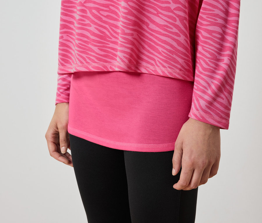 Detailaufnahme einer weiblichen Person mit einem rosafarbenen Oberteil mit Tiermuster und schwarzen Leggings.