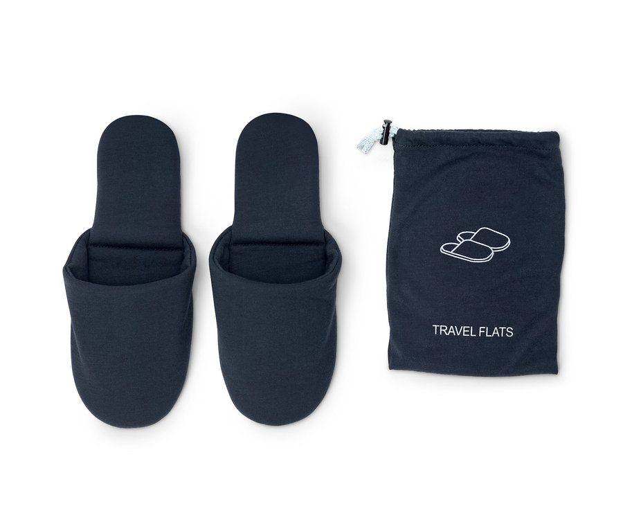 Zwei blaue Reise-Hausschuhe neben einem blauen Beutel.