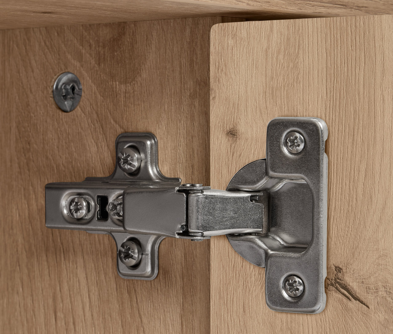 Detail eines silbernen Scharniers an einem hölzernen Sideboard »REET« mit Lamellenoptik.