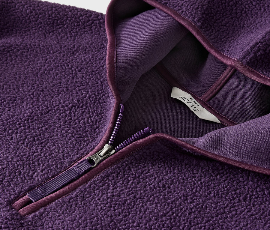 Detailansicht eines lila Fleece-Pullovers mit Reißverschluss und Etikett.