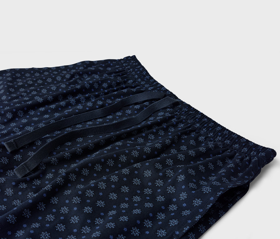 Nahaufnahme einer marineblauen Schlafanzughose mit blauem Blumenmuster und Kordelzug.