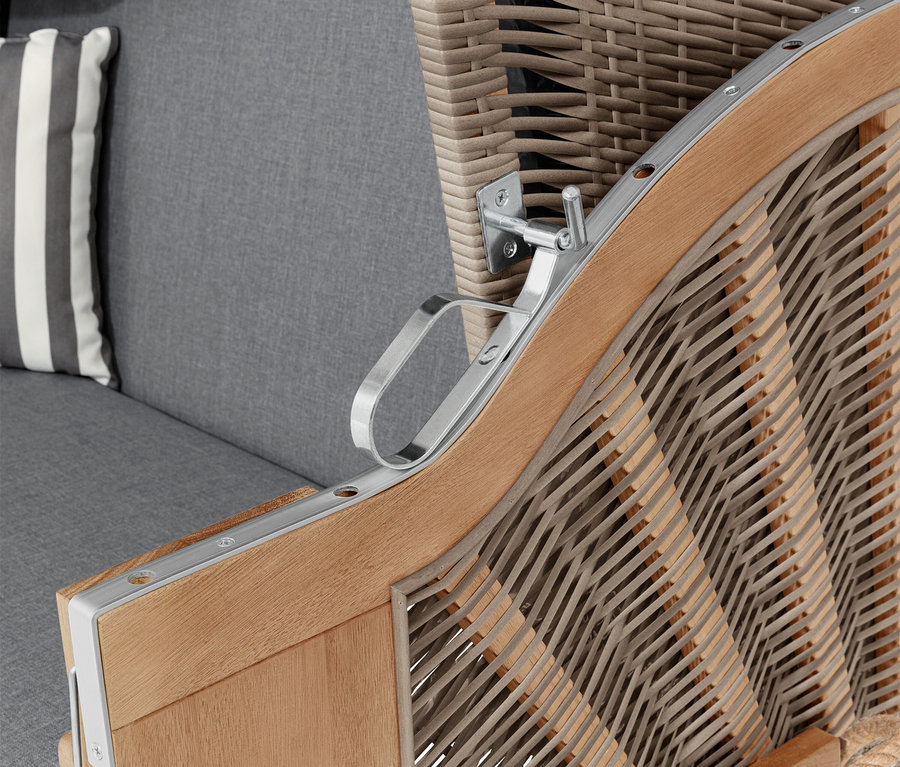 Detailaufnahme eines Strandkorbs mit Armlehne, grauem Kissen und gestreiftem Kissen.
