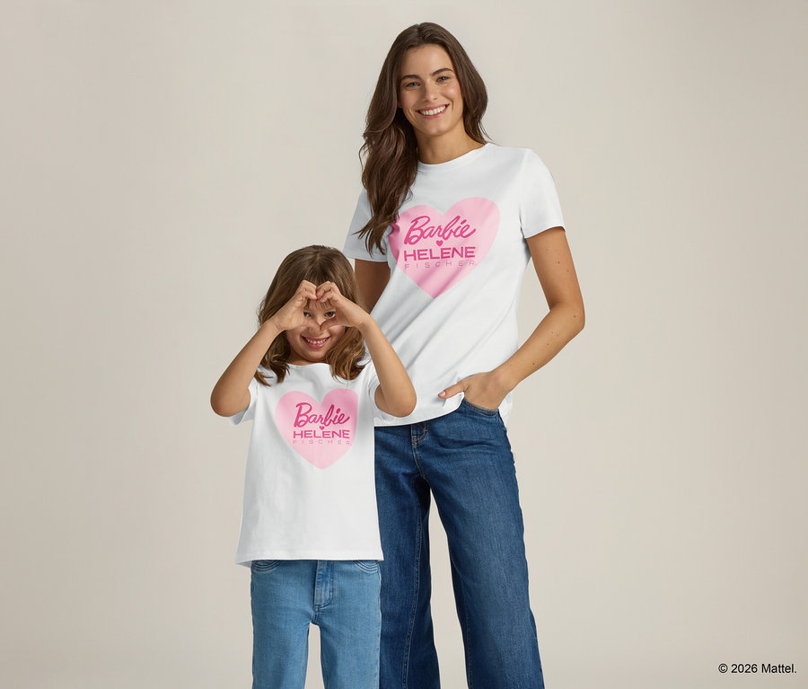 Lächelnde Frau und Mädchen mit Jeans und weißen T-Shirts mit rosafarbenem Barbie-Herz-Aufdruck posieren vor einem hellen Hintergrund.