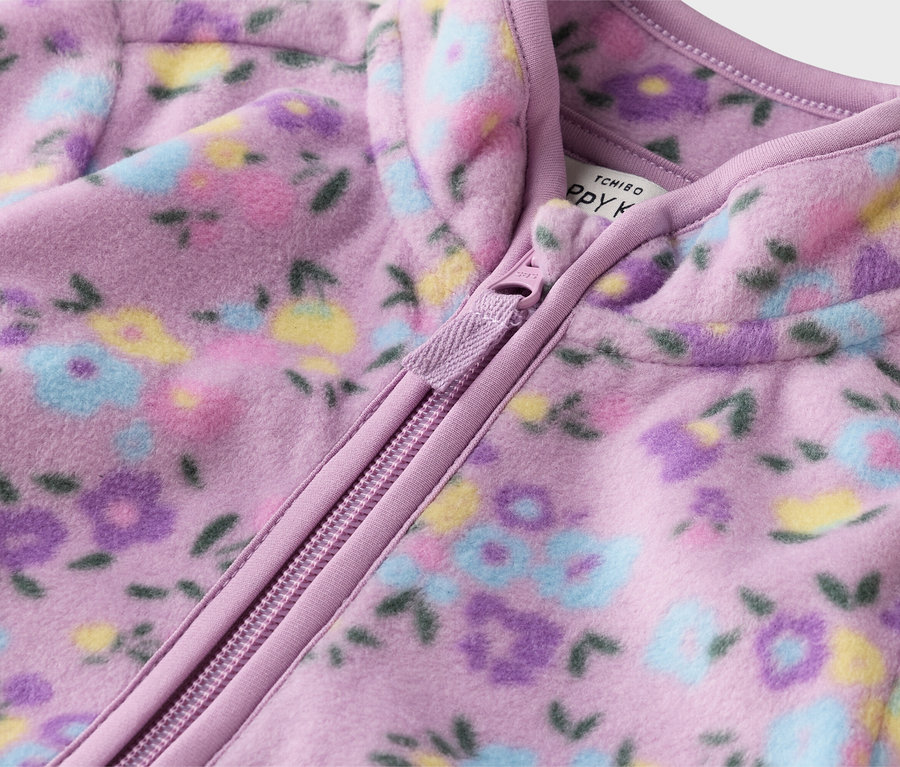 Nahaufnahme einer lila Fleecejacke mit Reißverschluss und Blumenmuster.