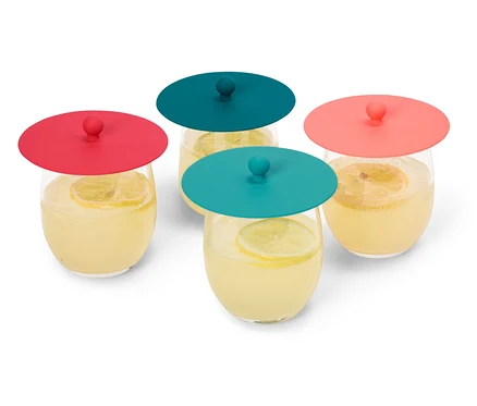 Vier Gläser Limonade mit Zitronenscheiben, abgedeckt mit roten und türkisfarbenen Silikondeckeln, stehen auf einem weißen Hintergrund.