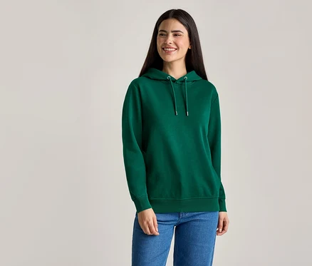 Frau mit langen, dunklen Haaren trägt einen grünen Kapuzenpullover und blaue Jeans.