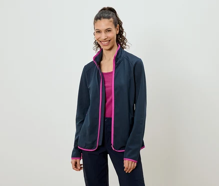 Frau mit Pferdeschwanz trägt eine marineblaue Fleecejacke mit pinkfarbenen Akzenten über einem pinkfarbenen Top und marineblauen Hosen.
