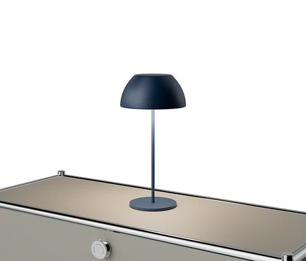 Eine blaue Lampe steht auf einem beigen Tisch mit silbernen Akzenten.