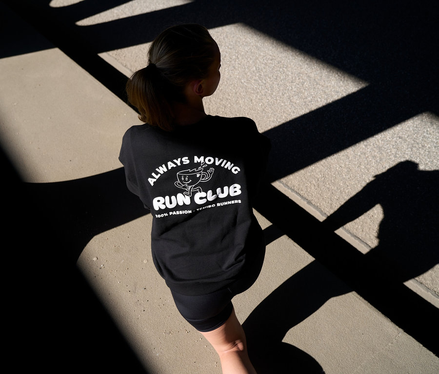 Person von hinten in schwarzem Sweatshirt mit „RUN CLUB“-Aufdruck und kurzen anthrazitfarbenen Sportleggings »ActivePower«.
